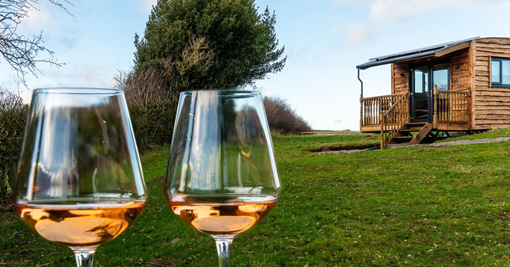 Two wine glasses with one of Cheesedale Shepherd's hut in the background